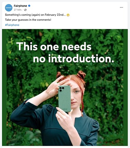 A red-haired woman is looking at the viewer while vertically holding a green speckled Fairphone 4 in front of one half of her face, seeminlgy aiming to take a photograph. The background consists of green bushes or trees. Over the woman’s head the line "This one needs no introduction." Over the picture the lines "Something’s coming (again) on February 22nd … [shhh emoji] Take your guesses in the comments!"